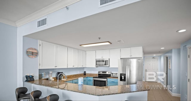 375 Beach Club Trl Unit A1704, Gulf Shores, AL 36542 - kitchen featuring appliances with stainless steel finishes, dark stone counters, a peninsula, white cabinets, and a kitchen bar