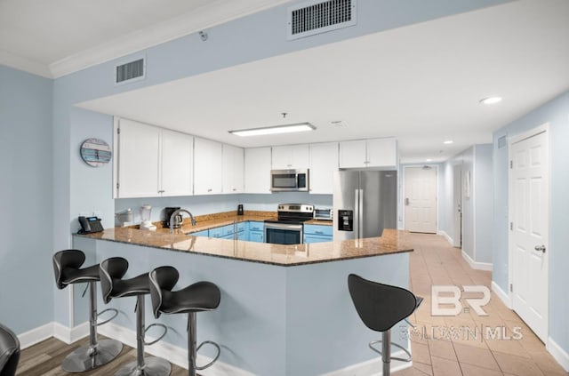 375 Beach Club Trl Unit A1704, Gulf Shores, AL 36542 - kitchen featuring appliances with stainless steel finishes, stone countertops, a breakfast bar area, a peninsula, and white cabinets