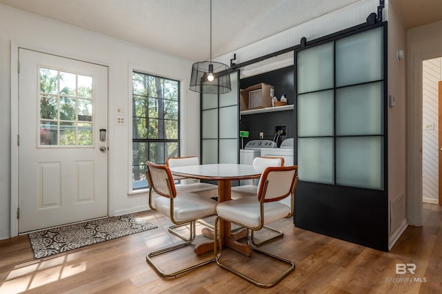 dining space with a barn door, visible vents, and wood finished floors