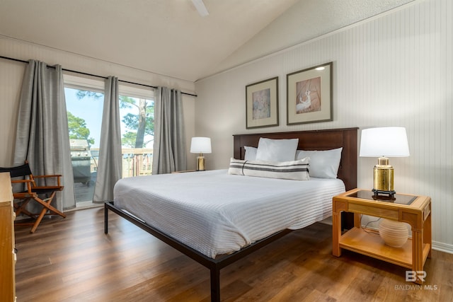 bedroom with lofted ceiling, wood finished floors, and access to outside