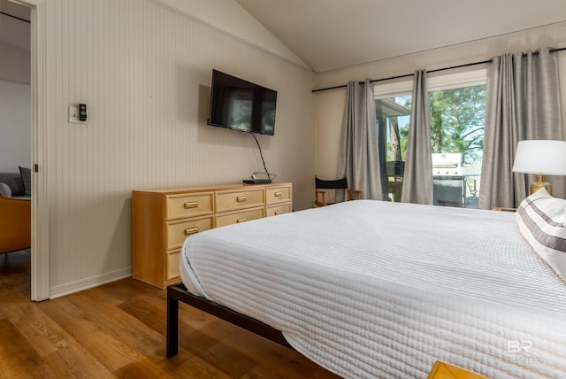 bedroom featuring light wood-style flooring, baseboards, lofted ceiling, and access to outside