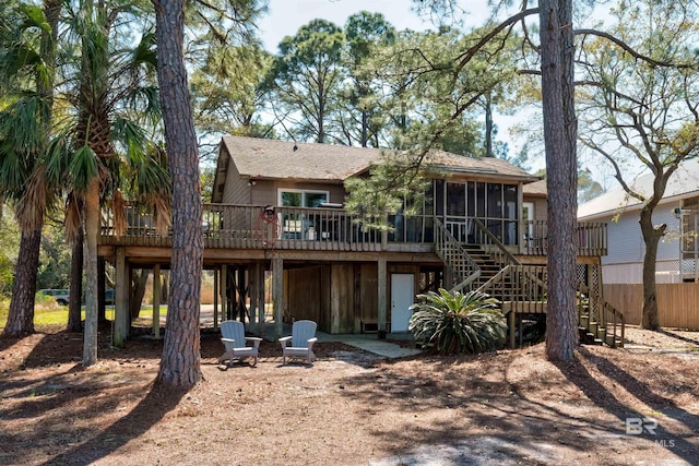 rear view of house featuring a wooden deck, stairs, roof with shingles, and a sunroom