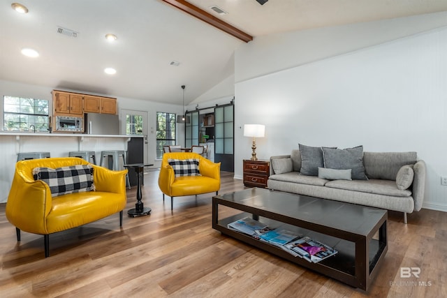 living area featuring lofted ceiling with beams, a wealth of natural light, visible vents, and light wood finished floors