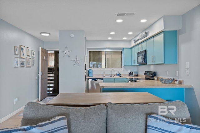 kitchen featuring visible vents, a sink, light countertops, appliances with stainless steel finishes, and blue cabinetry