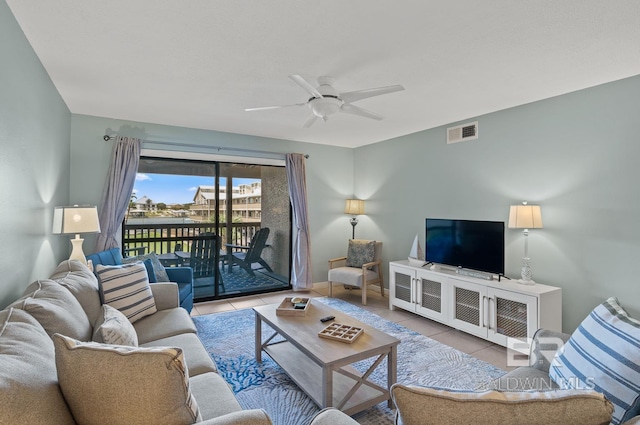 living room featuring tile patterned flooring, visible vents, baseboards, and a ceiling fan