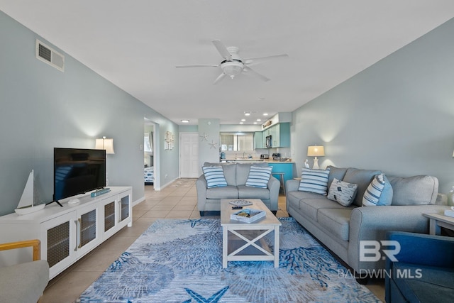 living area featuring light tile patterned floors, visible vents, baseboards, and a ceiling fan