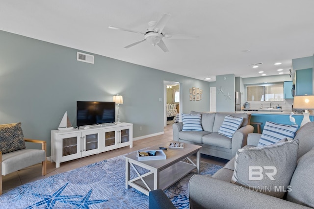 tiled living room with a ceiling fan, visible vents, recessed lighting, a sink, and baseboards