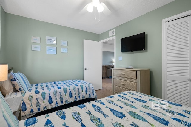 bedroom featuring visible vents, a closet, a ceiling fan, and light tile patterned flooring