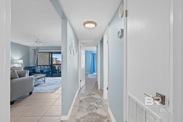 corridor featuring light tile patterned floors, visible vents, and baseboards