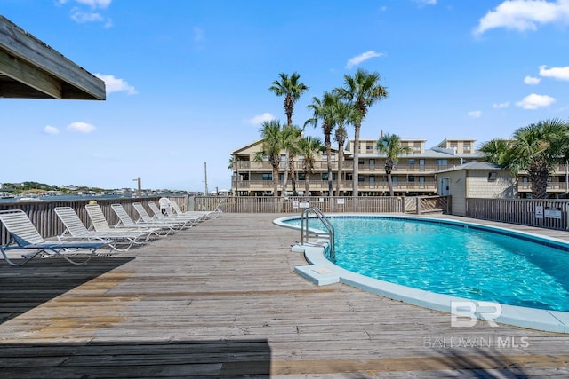 community pool with a wooden deck and fence