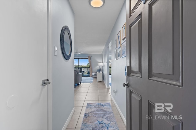 corridor featuring baseboards and light tile patterned flooring