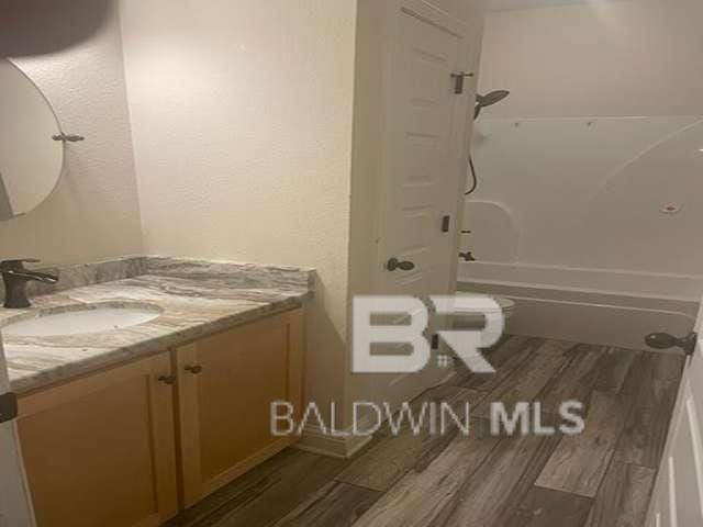 21800 Old Brady Rd, Robertsdale, AL 36567 - bathroom with wood finished floors, vanity, washtub / shower combination, and toilet