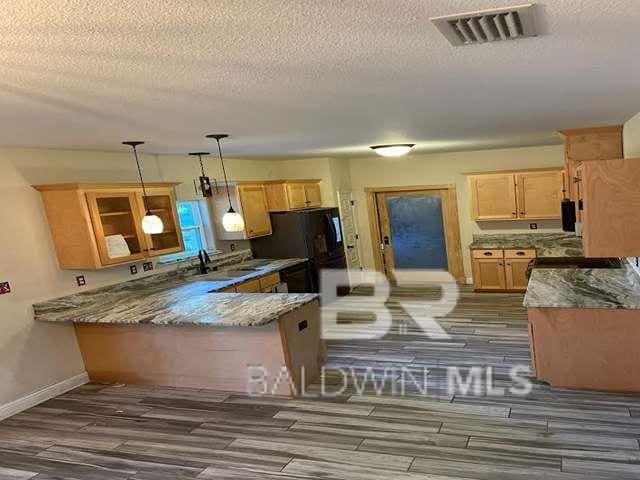 21800 Old Brady Rd, Robertsdale, AL 36567 - kitchen with wood finished floors, a peninsula, a textured ceiling, light stone countertops, and decorative light fixtures