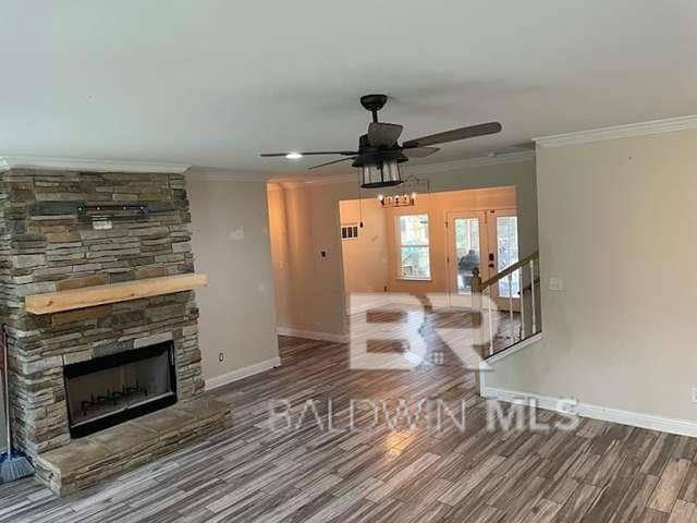 21800 Old Brady Rd, Robertsdale, AL 36567 - unfurnished living room with ceiling fan, ornamental molding, baseboards, wood finished floors, and a stone fireplace