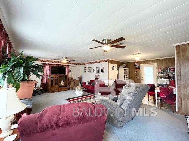 carpeted living room with wooden walls and ceiling fan