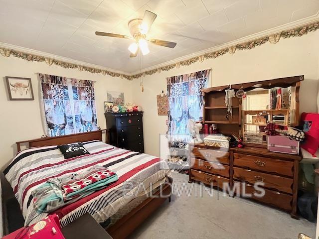 carpeted bedroom with ceiling fan and ornamental molding