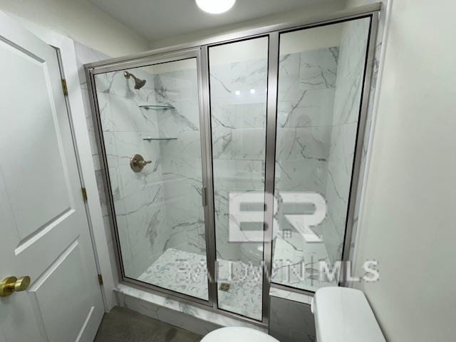 bathroom featuring a shower with door and toilet