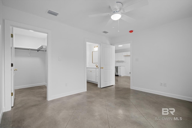 unfurnished bedroom featuring a spacious closet, ceiling fan, a closet, and connected bathroom