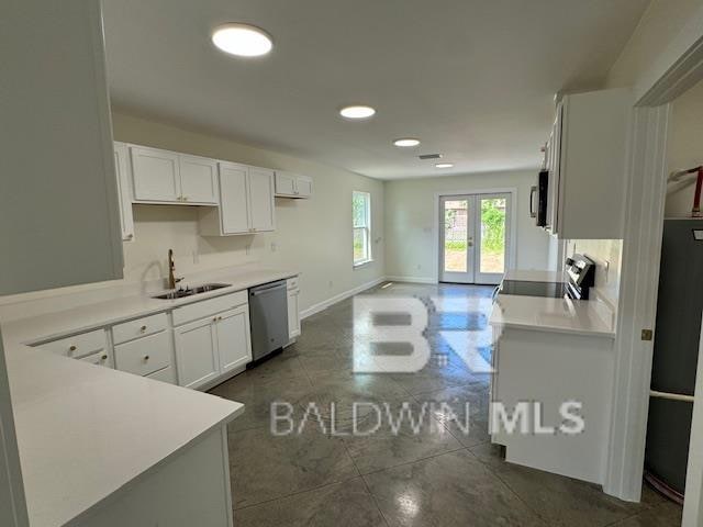 kitchen with sink, dark tile patterned floors, french doors, white cabinetry, and appliances with stainless steel finishes