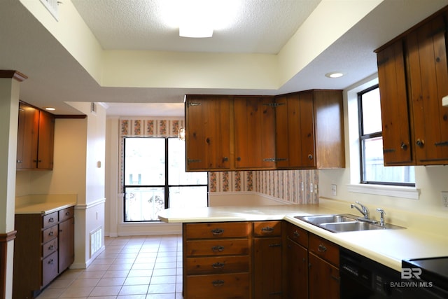 kitchen featuring sink, dishwasher, a textured ceiling, light tile patterned flooring, and kitchen peninsula