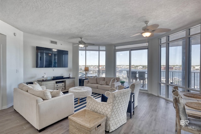 27405 Polaris St Unit 302, Orange Beach, AL 36561 - living area with ceiling fan, wood finished floors, a textured ceiling, baseboards, and a wall of windows