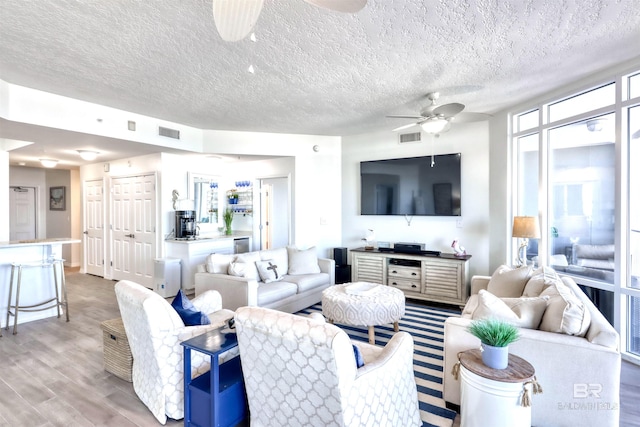 27405 Polaris St Unit 302, Orange Beach, AL 36561 - living room featuring ceiling fan, light wood finished floors, and a textured ceiling