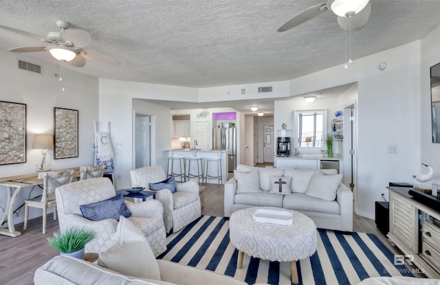 27405 Polaris St Unit 302, Orange Beach, AL 36561 - living room with ceiling fan, light wood finished floors, and a textured ceiling