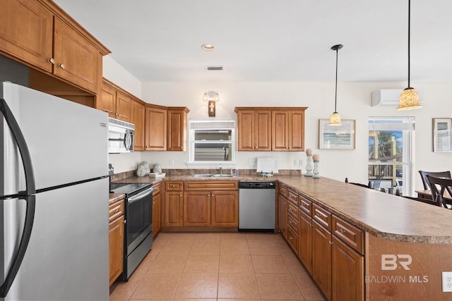kitchen featuring a peninsula, brown cabinets, a sink, and appliances with stainless steel finishes