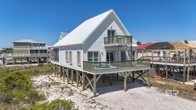 back of house with a carport, metal roof, driveway, and a balcony
