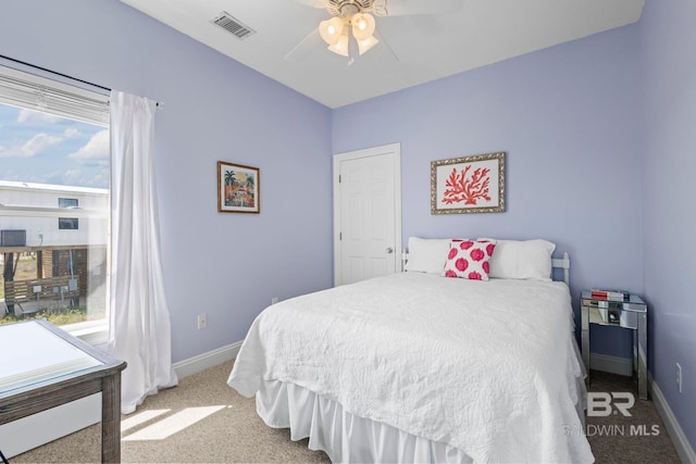 carpeted bedroom featuring visible vents, baseboards, multiple windows, and ceiling fan