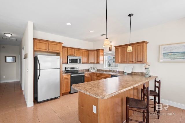kitchen with brown cabinetry, appliances with stainless steel finishes, a peninsula, and baseboards