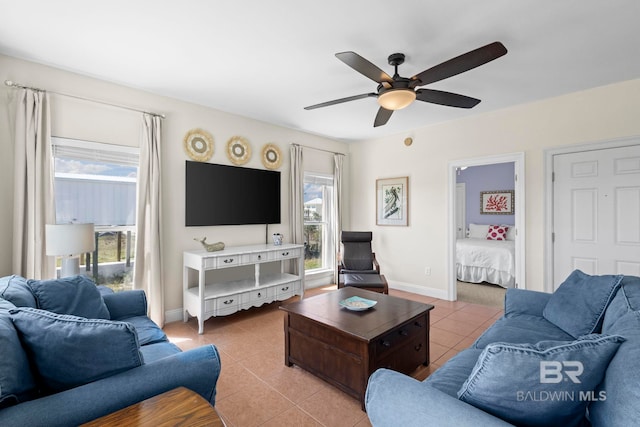 living area featuring light tile patterned floors, baseboards, and a ceiling fan