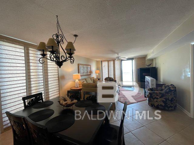 tiled dining room featuring ceiling fan with notable chandelier, floor to ceiling windows, and a textured ceiling