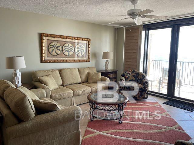 living room with floor to ceiling windows, light tile patterned floors, ceiling fan, and a textured ceiling