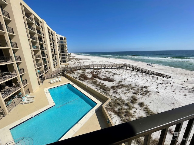 view of swimming pool featuring a water view and a beach view