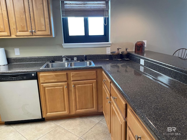 kitchen with dark stone counters, dishwasher, sink, and light tile patterned floors