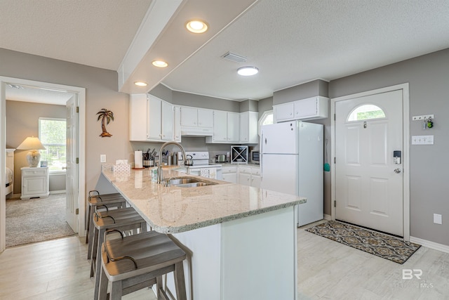 9581 S Bay Rd, Foley, AL 36535 - kitchen featuring sink, white cabinets, kitchen peninsula, light stone countertops, and white appliances
