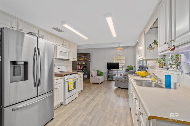 kitchen featuring ceiling fan, light hardwood / wood-style floors, sink, white appliances, and white cabinets