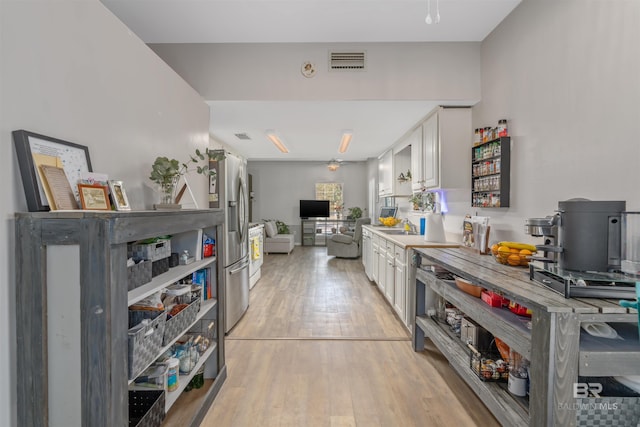 kitchen featuring stainless steel refrigerator with ice dispenser, white cabinetry, light hardwood / wood-style floors, and sink