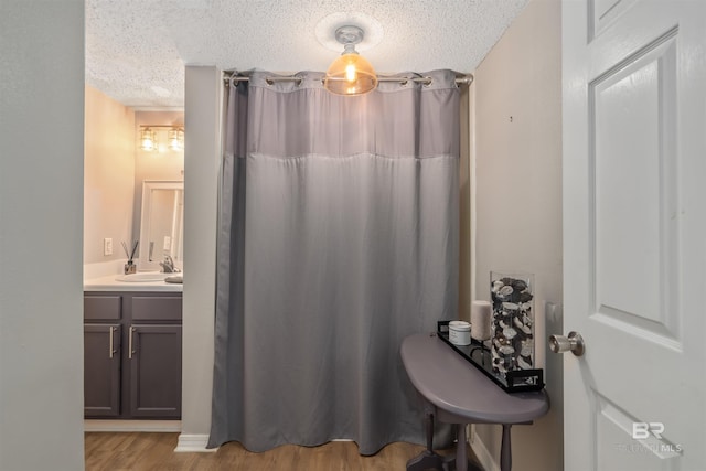 bathroom with a textured ceiling, wood-type flooring, and vanity