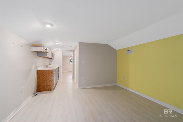 bonus room with light wood-type flooring, vaulted ceiling, and sink