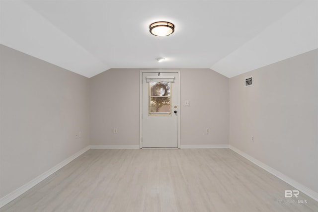 additional living space featuring vaulted ceiling and light wood-type flooring