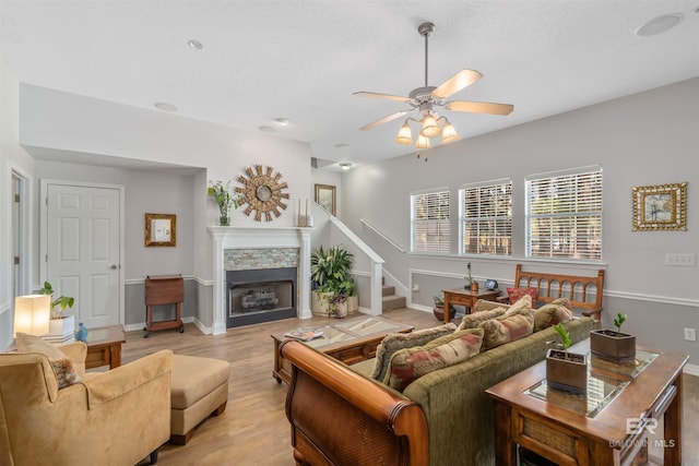 living room featuring a fireplace, light hardwood / wood-style floors, and ceiling fan