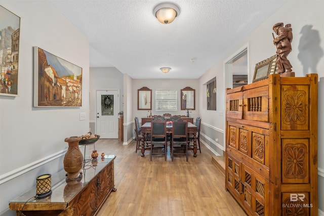 dining space featuring a textured ceiling and light hardwood / wood-style floors