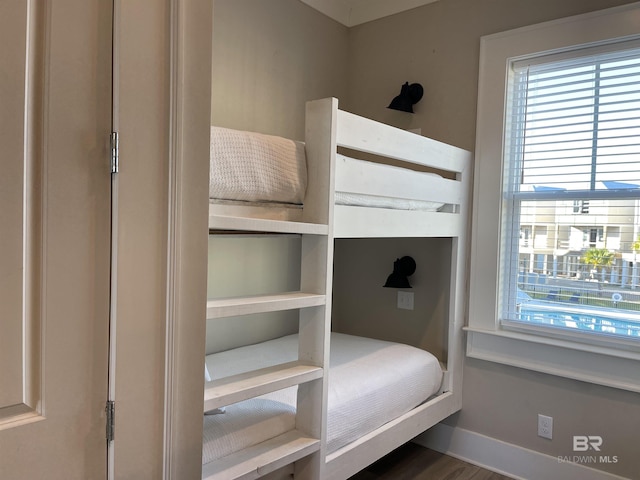 bedroom with wood finished floors, baseboards, and multiple windows