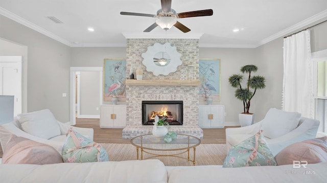 living room featuring a fireplace, ornamental molding, ceiling fan, and light wood-type flooring