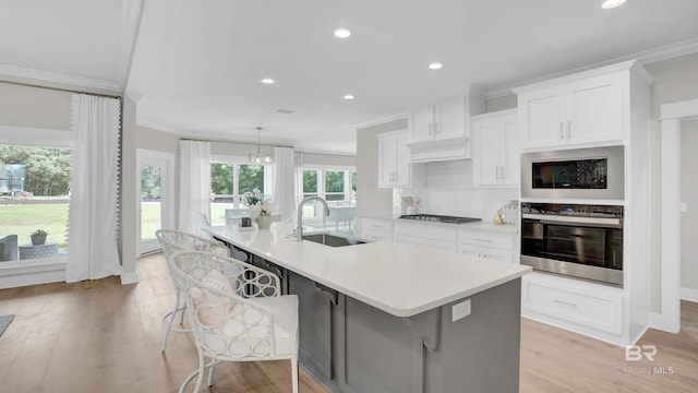 kitchen with stainless steel appliances, a kitchen breakfast bar, a large island with sink, and white cabinets