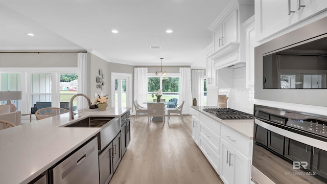 kitchen with pendant lighting, sink, white cabinetry, backsplash, and stainless steel appliances