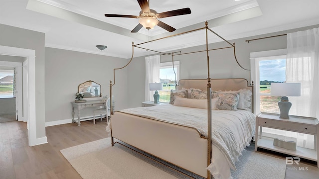 bedroom with hardwood / wood-style flooring, crown molding, ceiling fan, and a tray ceiling