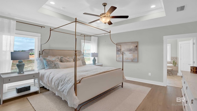 bedroom featuring a tray ceiling, ornamental molding, ceiling fan, and hardwood / wood-style flooring